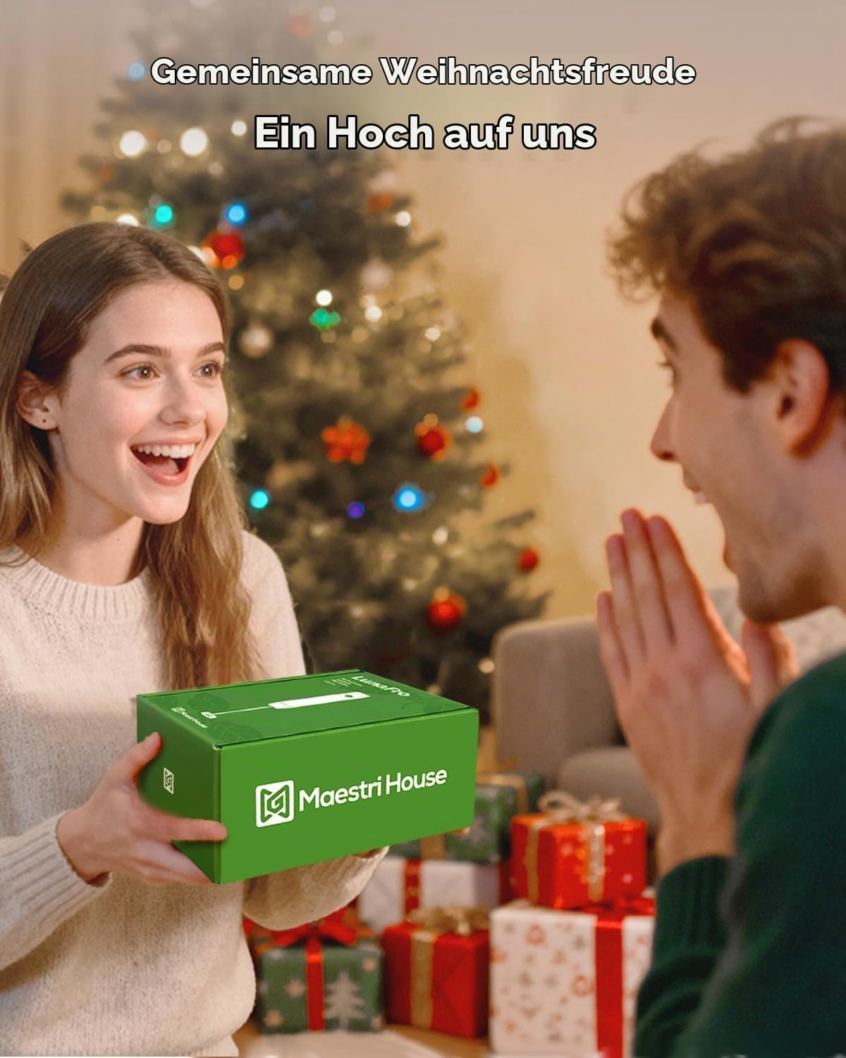 Eine Frau schenkt einem Mann vor einem Weihnachtsbaum ein grünes Maestri House-Paket.