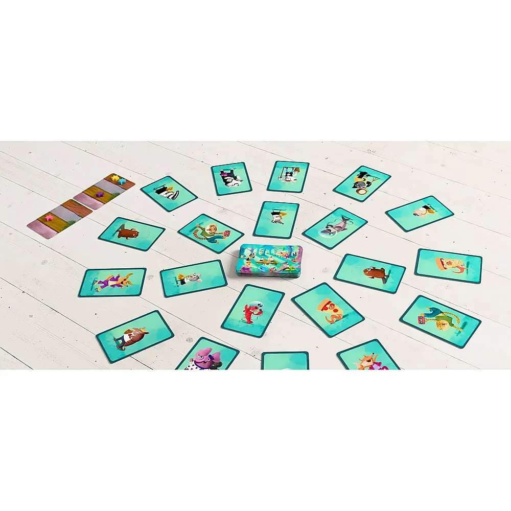 Buntes Kartenspiel ausgebreitet auf hellem Holzboden mit Karten im Kreis und Spielplan links.