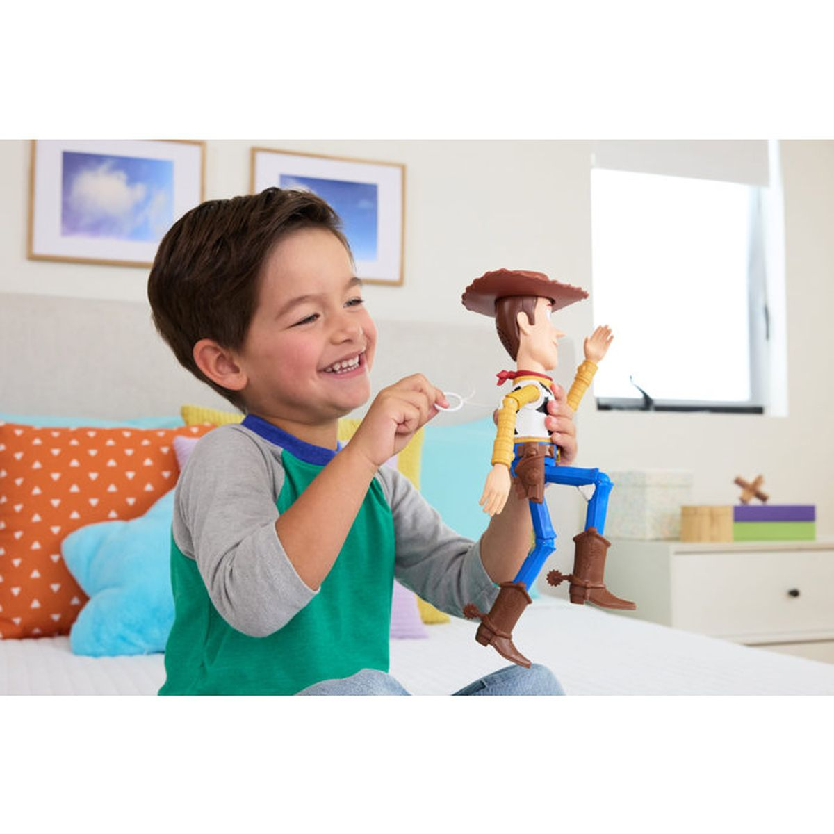 Ein glücklicher Junge sitzt auf dem Bett und spielt mit einer Woody-Figur aus Toy Story.