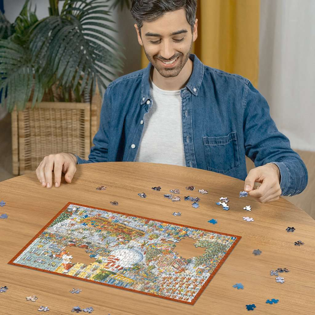 Ein lächelnder Mann sitzt an einem Holztisch und setzt ein großes Puzzle zusammen.