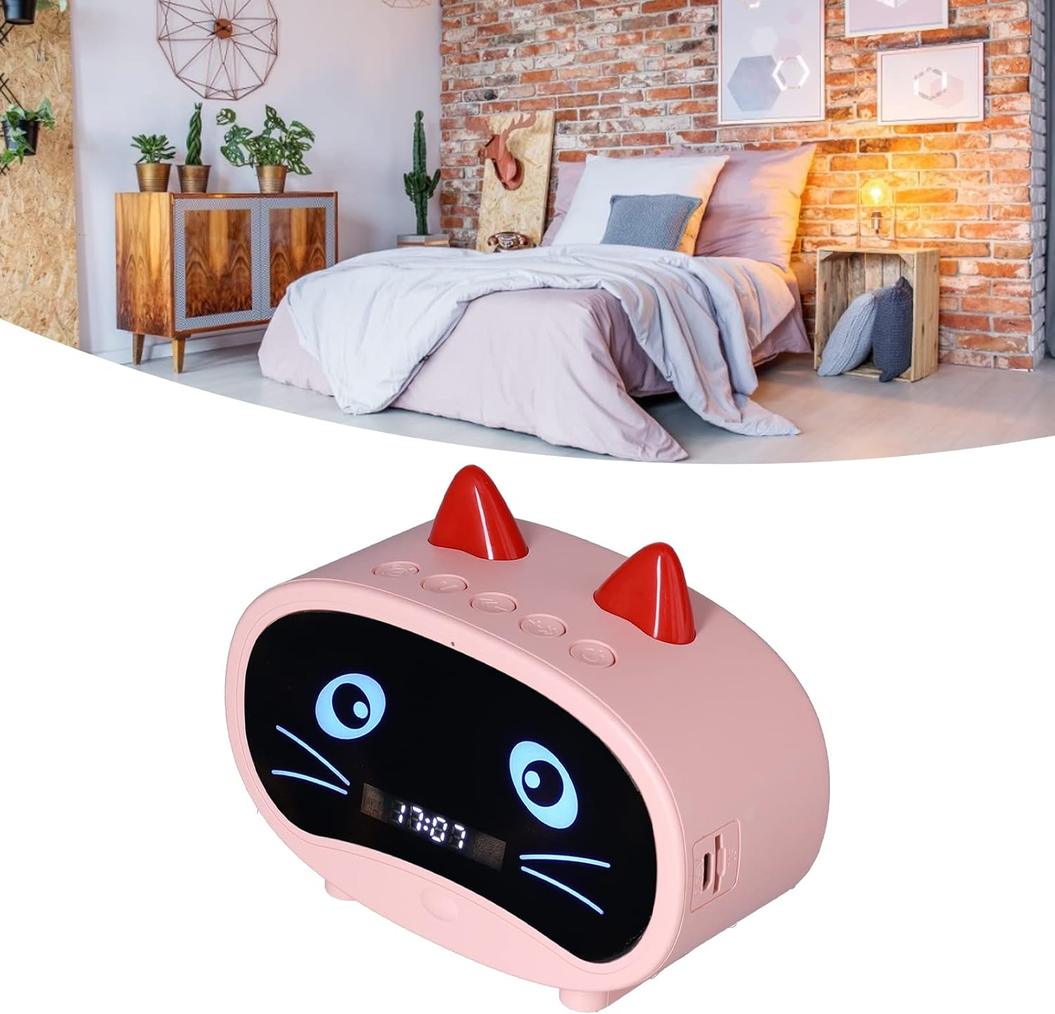Ein rosafarbener Wecker im Katzen-Design mit blauen Leuchtaugen und roten Ohren steht vor einem schlafenden Bett.
