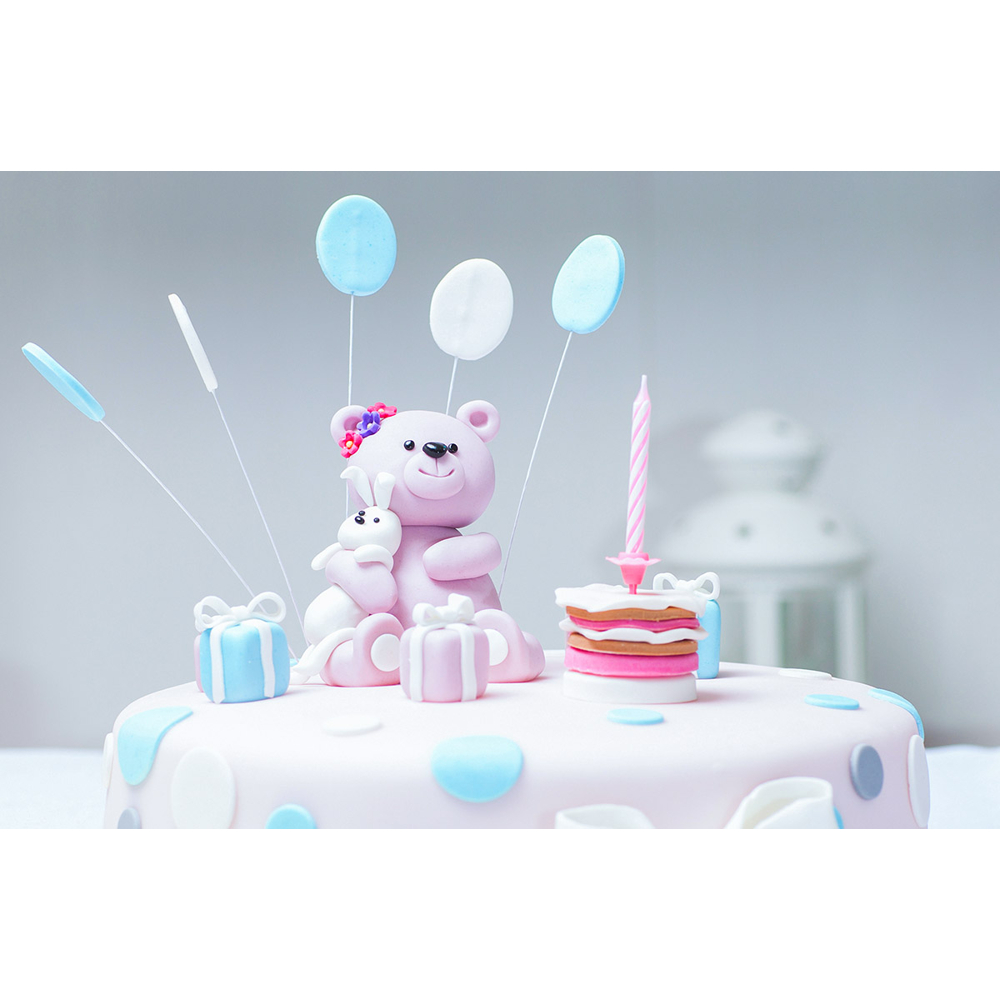 Rosa Geburtstagstorte mit einem rosa Fondantbären, Geschenken, Ballons und einer Kerze.