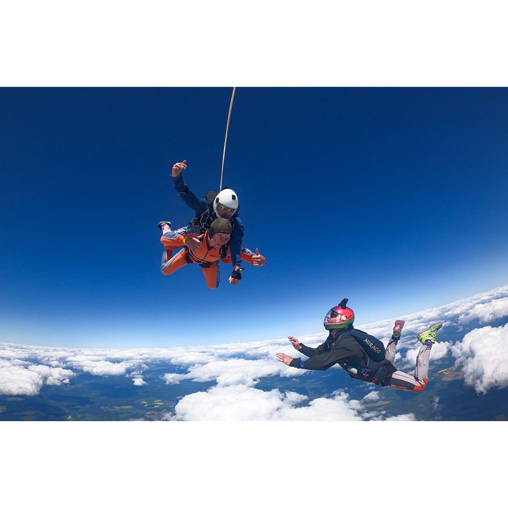 Zwei Fallschirmspringer stürzen durch den blauen Himmel über einer weißen Wolkendecke.