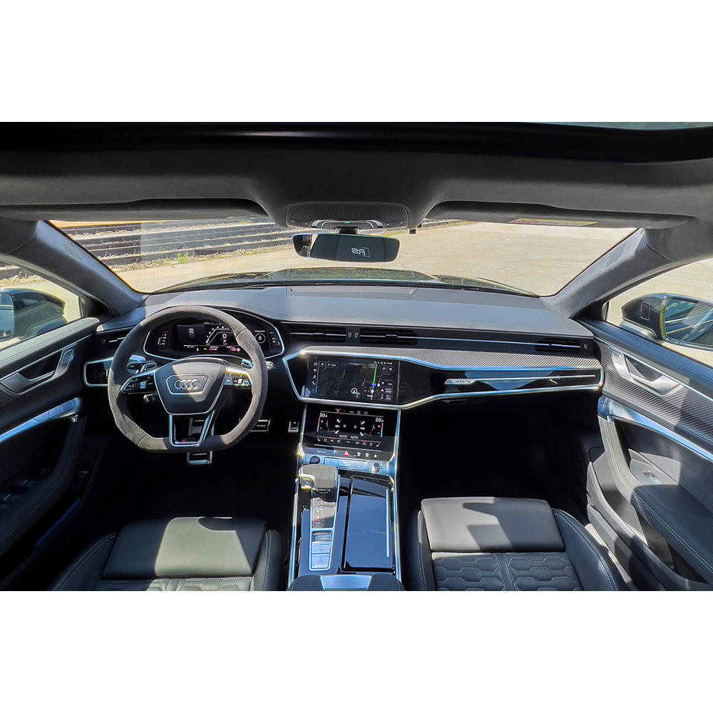 Moderne Audi-Innenausstattung mit Lenkrad, Displays und schwarzen Ledersitzen vor einer Freifläche.