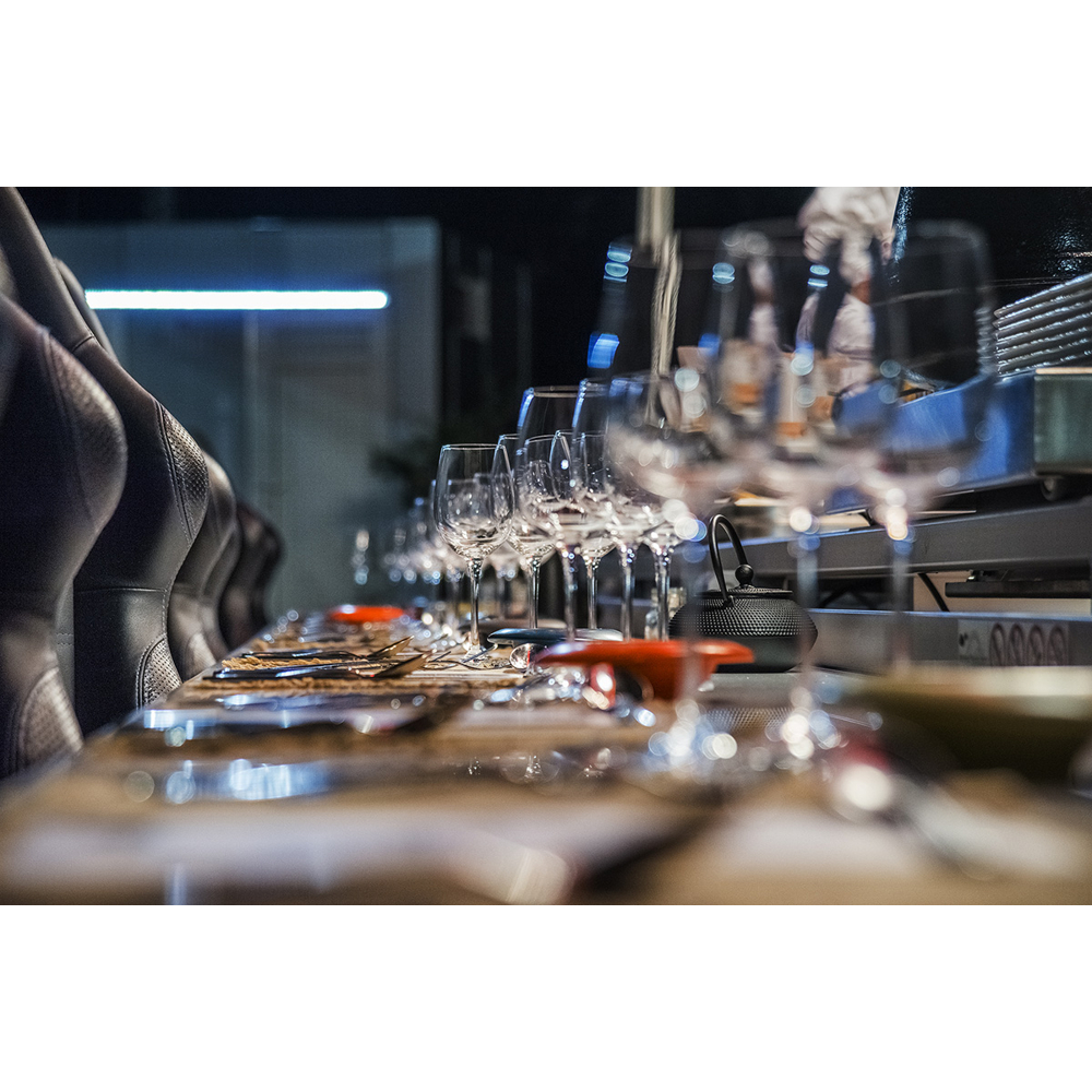 Ein elegant gedeckter Tisch in einem Restaurant mit Weingäsern und schwarzen Sitzen im Vordergrund.