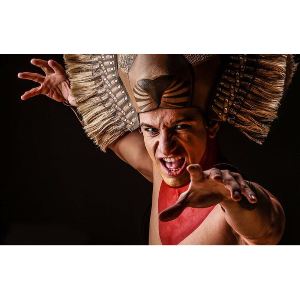 Ein Schauspieler mit Tiermaske und roter Bemalung faucht wild in die Kamera.
