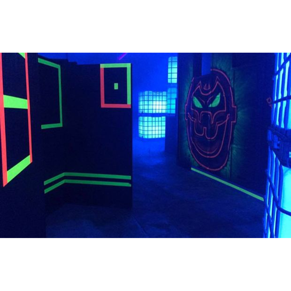Ein dunkler Raum mit Neonfarben und einer großen Teufelsmasken-Grafik an der Wand, beleuchtet durch Schwarzlicht.