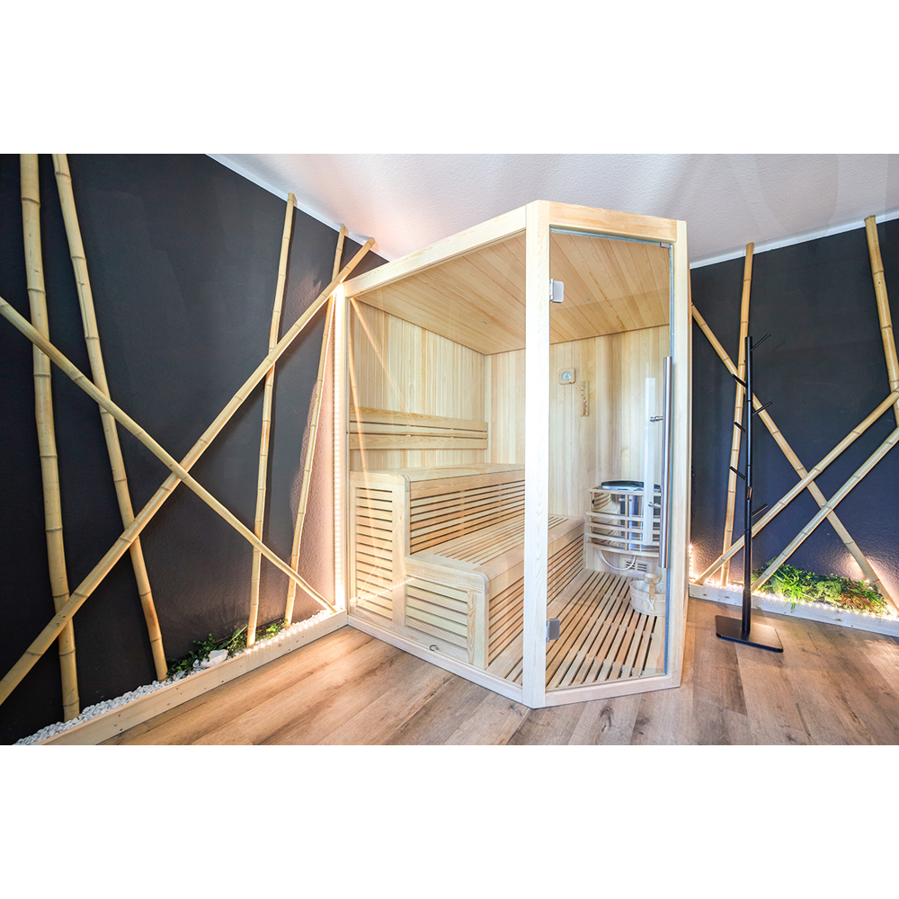 Eine Heimsauna aus Holz mit Glasfront in einem Raum mit dunklen Wänden, Bambusstäben und hellem Holzboden.