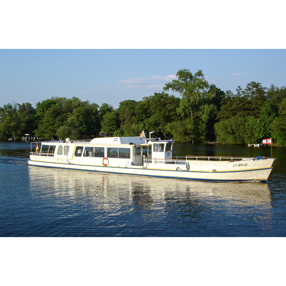 Ein weißes Passagierboot namens La Belle fährt auf einem ruhigen Fluss vorbei an grünen Ufern.