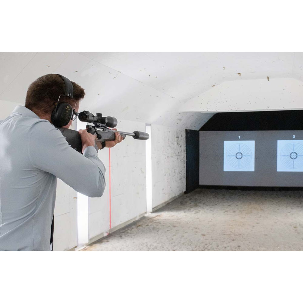Ein Mann mit Gehörschutz zielt mit einem Gewehr mit Zielfernrohr auf zwei elektronische Ziele.