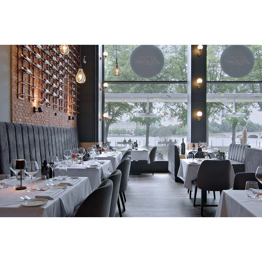 Elegantes Restaurant mit Backsteinwand, Weingestell und großen Fenstern mit Seeblick.