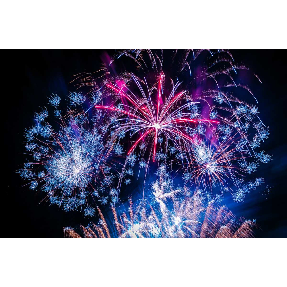 Bunte Feuerwerke leuchten in kräftigem Blau, Rosa und Weiß gegen einen dunklen Nachthimmel.