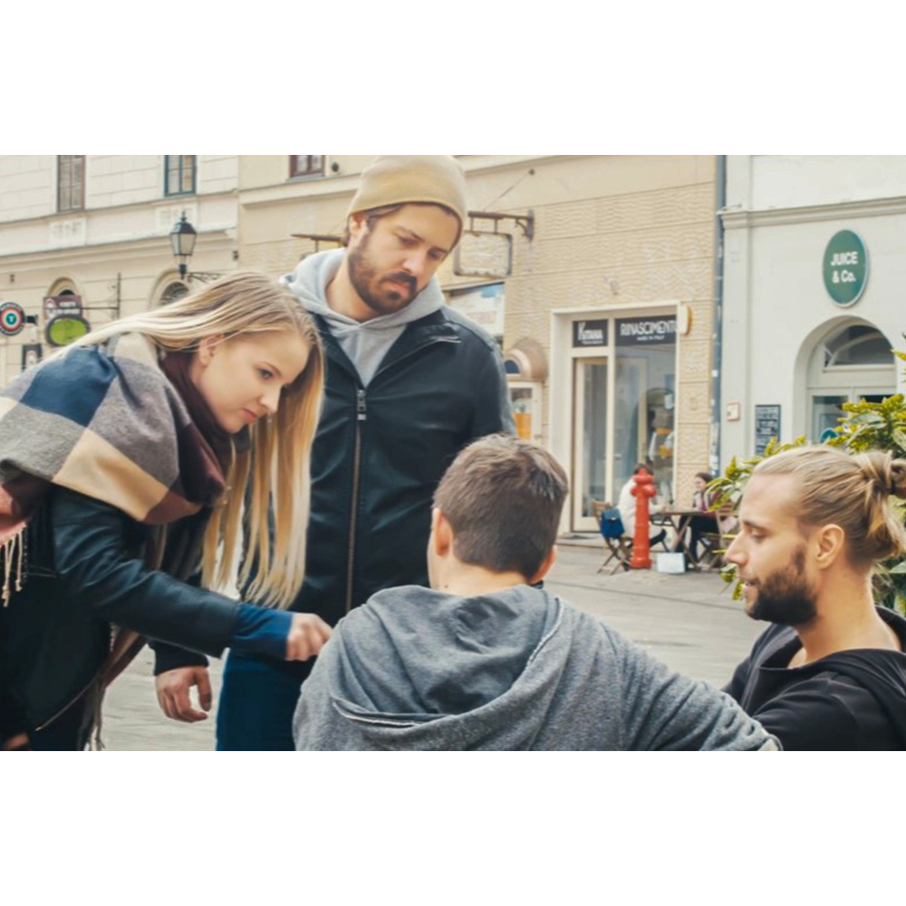 Vier Freunde versammeln sich in einer Stadtstraße und blicken inmitten von Geschäften konzentriert nach unten.