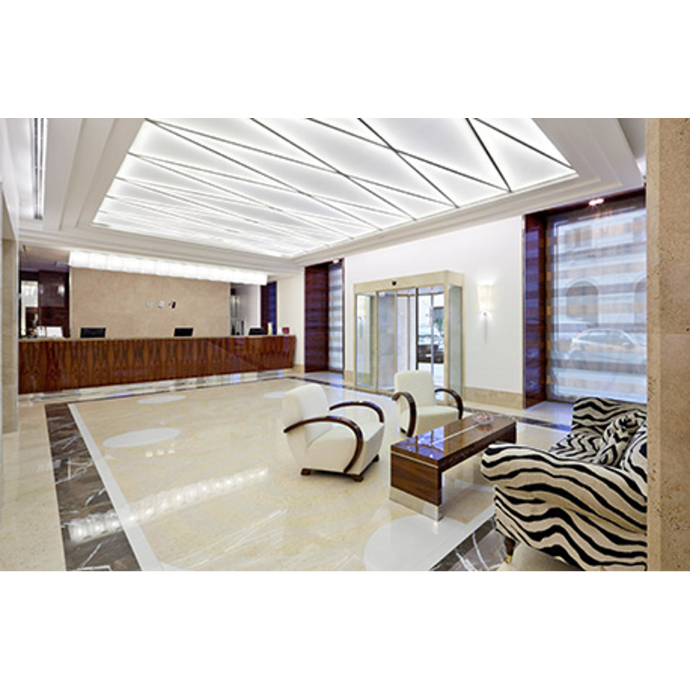 Moderne Hotelhalle mit Rezeption, weißem und Zebramuster-Sitzbereich sowie geometrischer Deckenbeleuchtung.