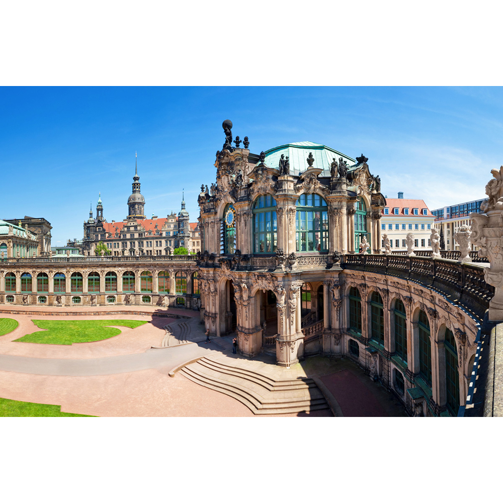 Der prunkvolle Barockpalast Zwinger in Dresden unter klarem blauen Himmel, mit Hof und Skulpturen.