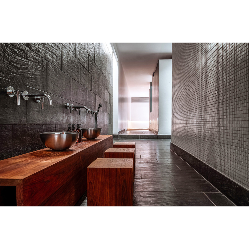 Moderne Sanitäranlage mit Holztresen, Waschbecken aus Edelstahl und dunklen Fliesenwänden.