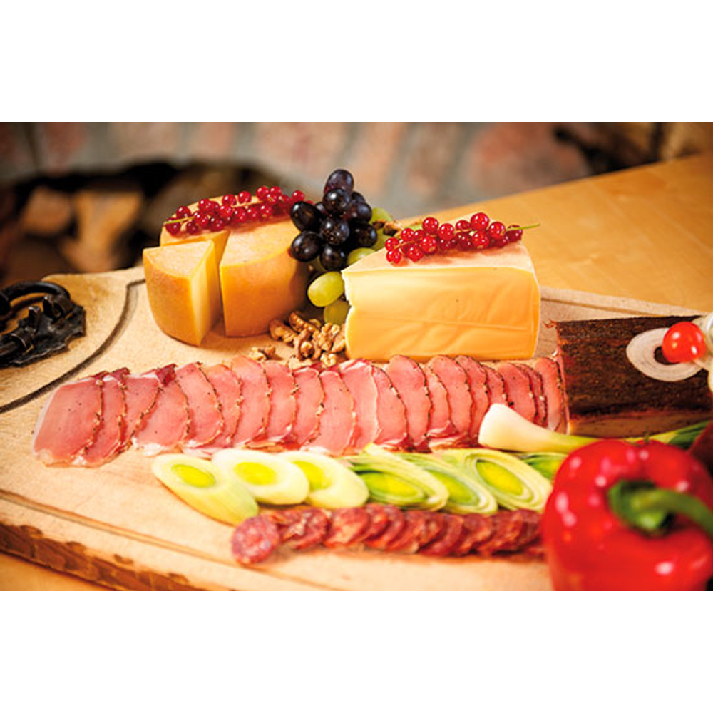 Wurstbrett mit Aufschnitt, Käse, Trauben, Lauch und einer roten Paprika.