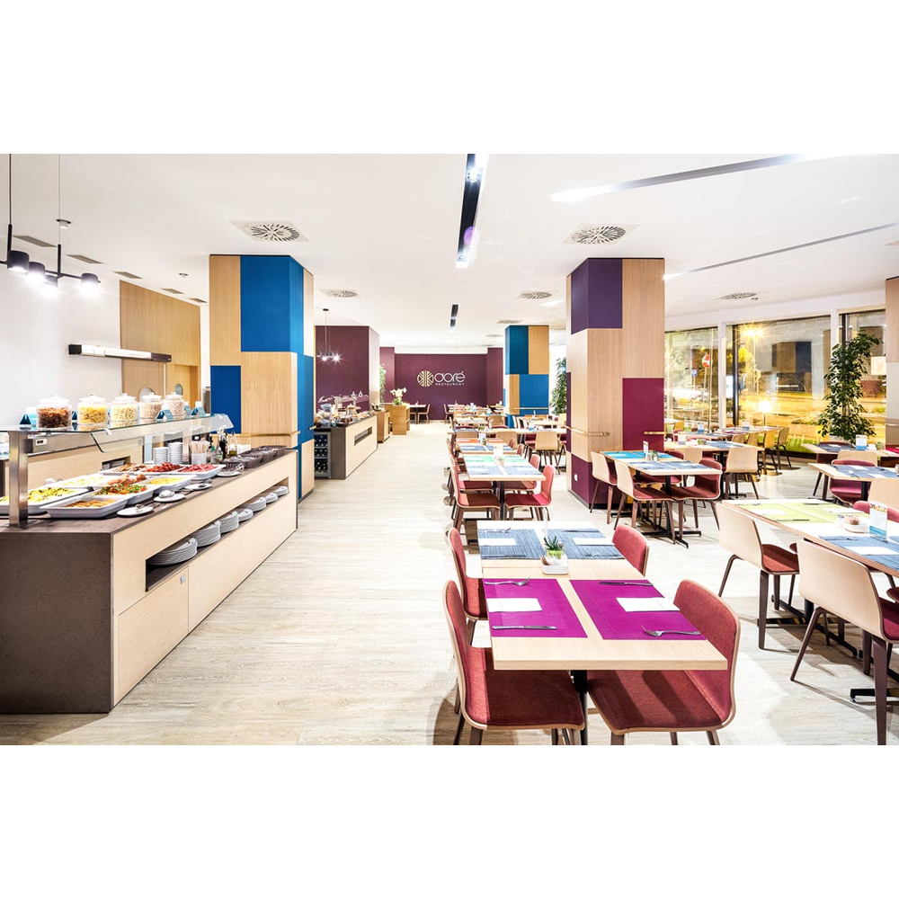 Moderne Restaurant-Innenansicht mit einem reichhaltigen Buffet auf der linken Seite und vielen gedeckten Tischen.