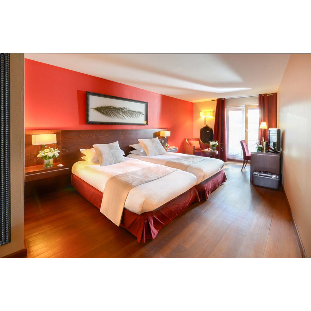 Ein Hotelzimmer mit zwei Einzelbetten, Holzböden, einer roten Akzentwand, einem gerahmten Blattbild und Schreibtisch.