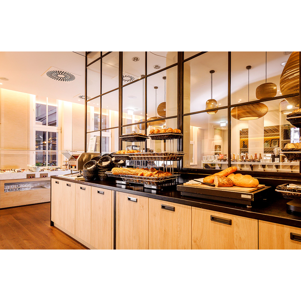 Eine Buffettheke mit Holzschränken, frischem Brot in Regalen und einer großen Glastrennwand im Hintergrund.