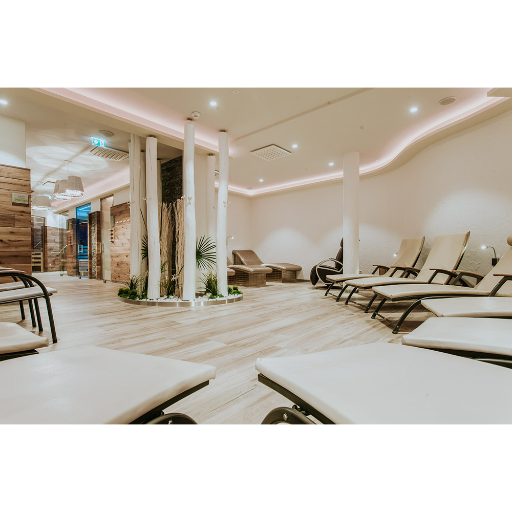 Moderne Spa-Ruhezone mit hellen Liegen, Holzböden und dekorativen weißen Baumstämmen.