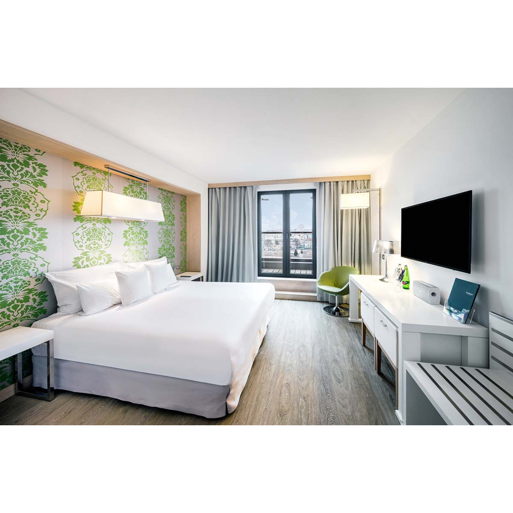 Moderne Hotelzimmer mit großem Bett, Fernseher, Schreibtisch und grünem Akzentmuster an der Wand.