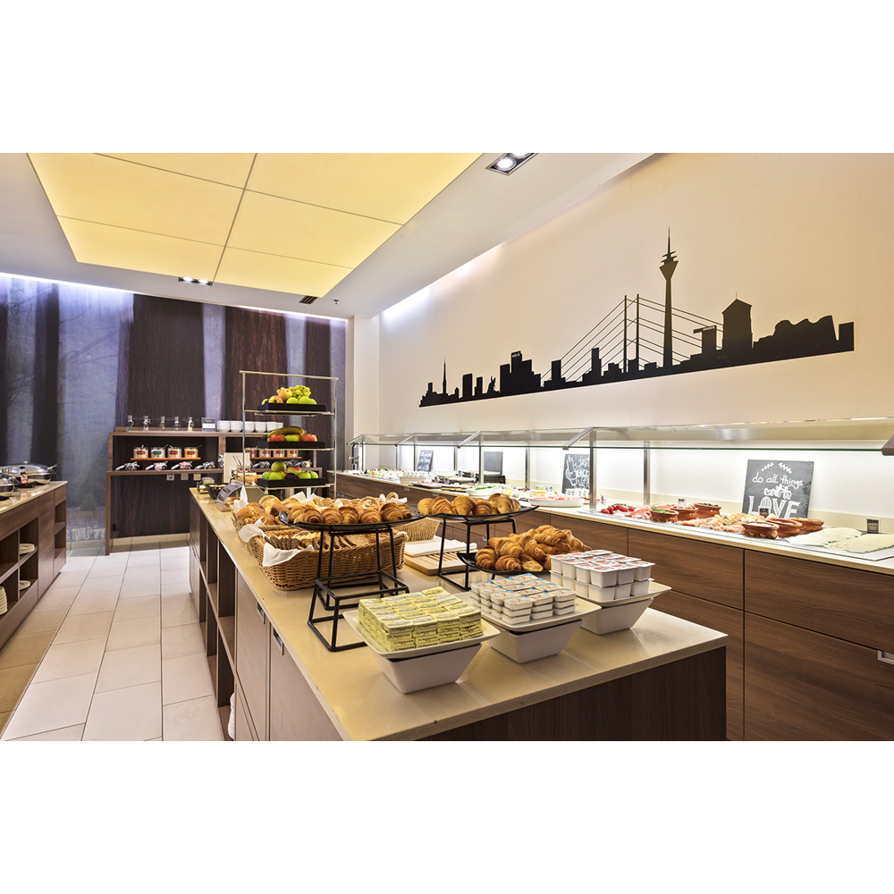Ein Frühstücksbuffet mit Backwaren, Butter und Früchten, an einer Wand mit Skyline-Silhouette.