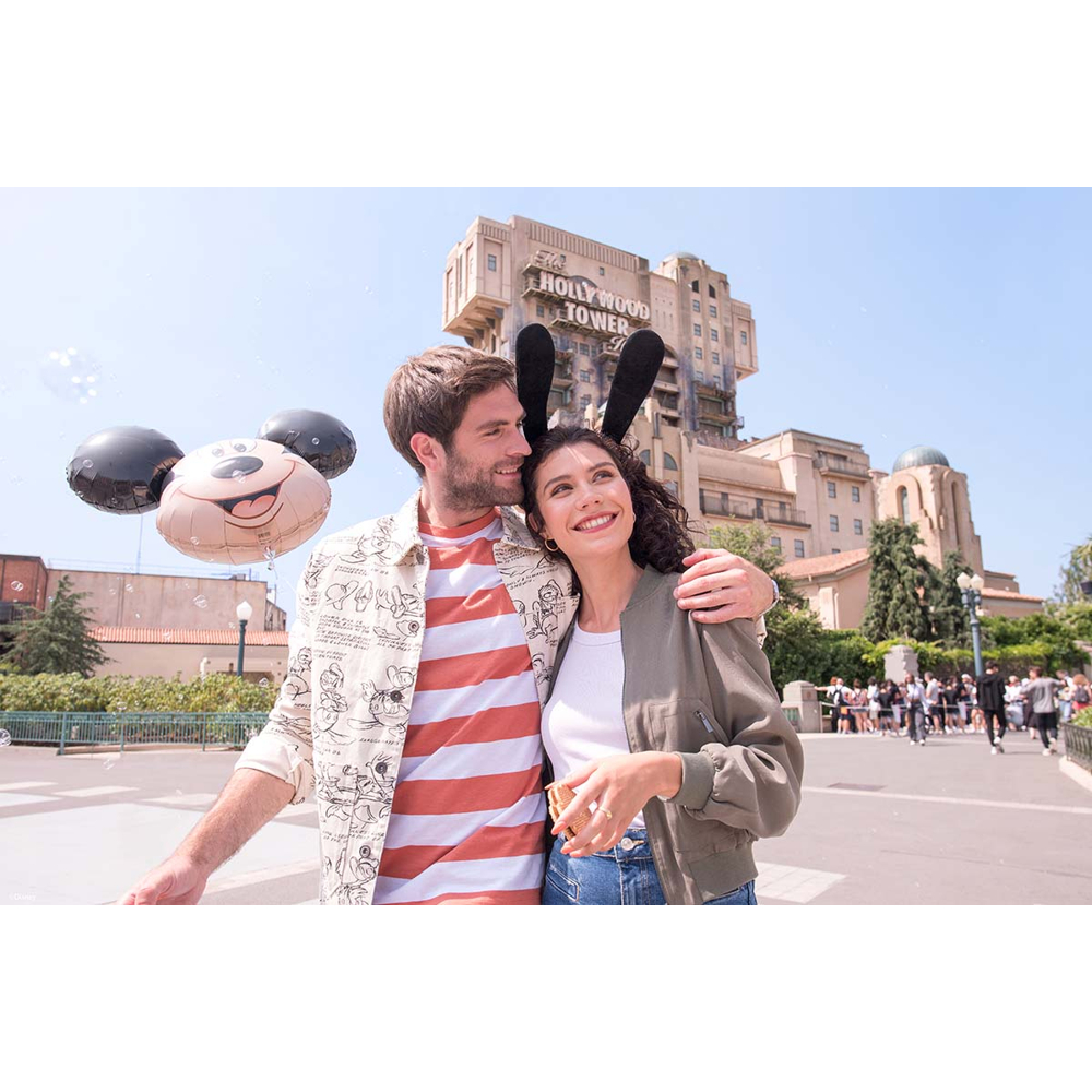 Paar umarmt sich vor dem Hollywood Tower mit Mickey-Maus-Ballon.