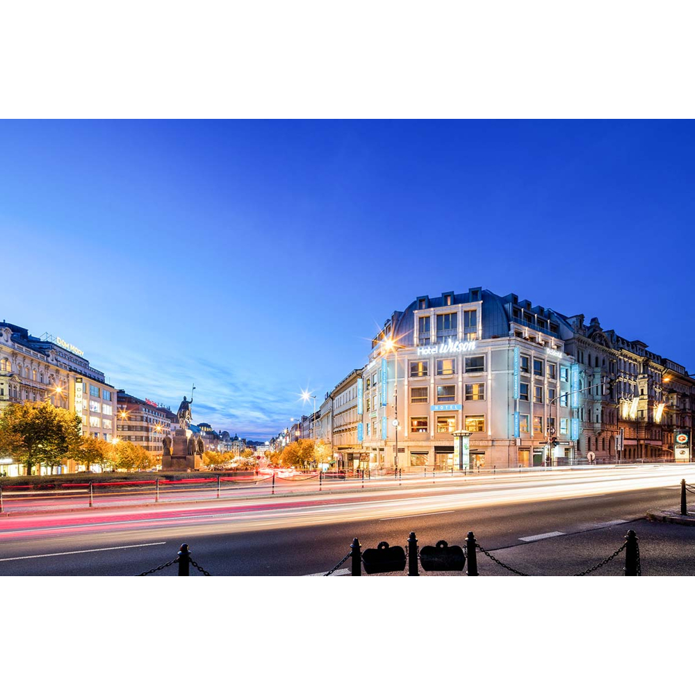 Beleuchtete Stadtstraße bei Dämmerung mit Hotel und Verkehrsschweiflichtern.