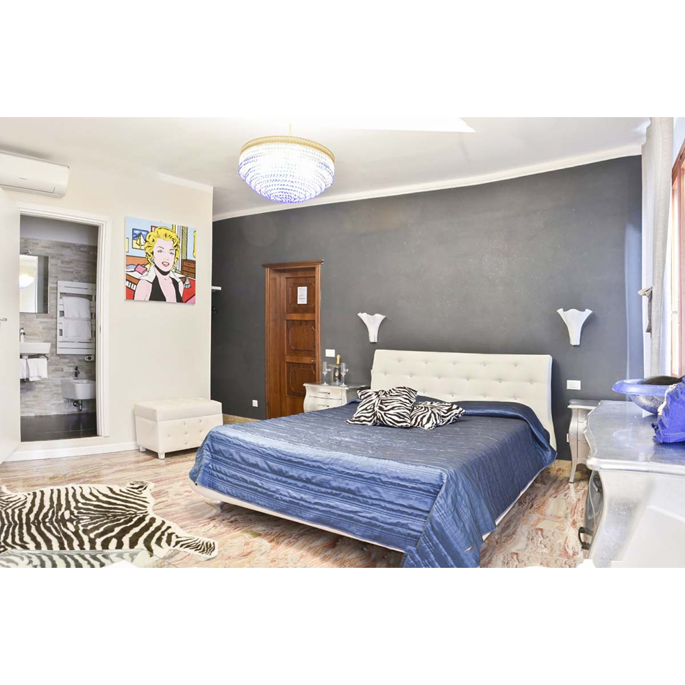 Luxuriöses Schlafzimmer mit dunkelblauem Bett, Zebra-Teppich, grauem Wand und Pop-Art-Bild.