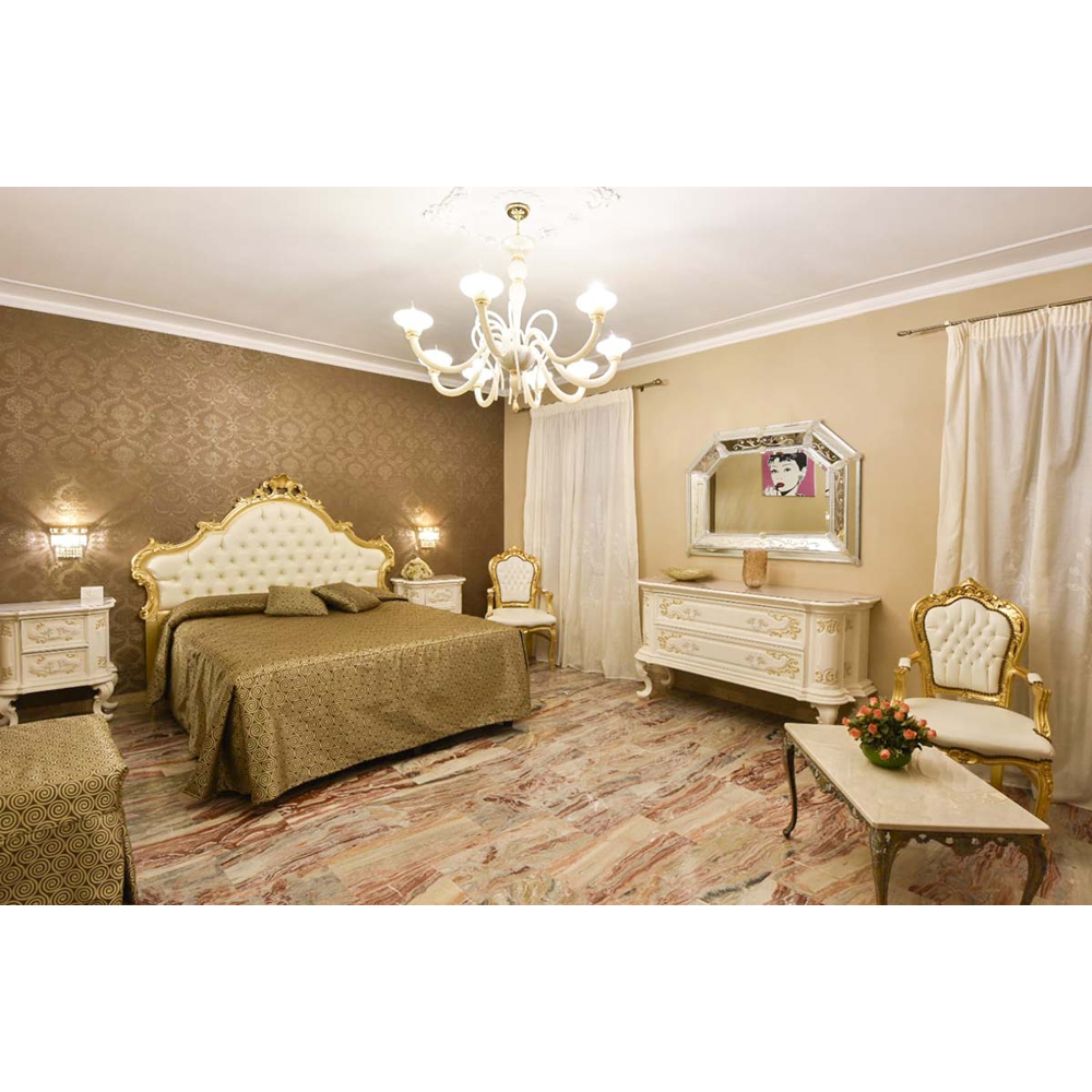 Ein luxuriöses Schlafzimmer mit großem Bett, goldenen Möbeln, Kronleuchter und gemustertem Marmorboden.