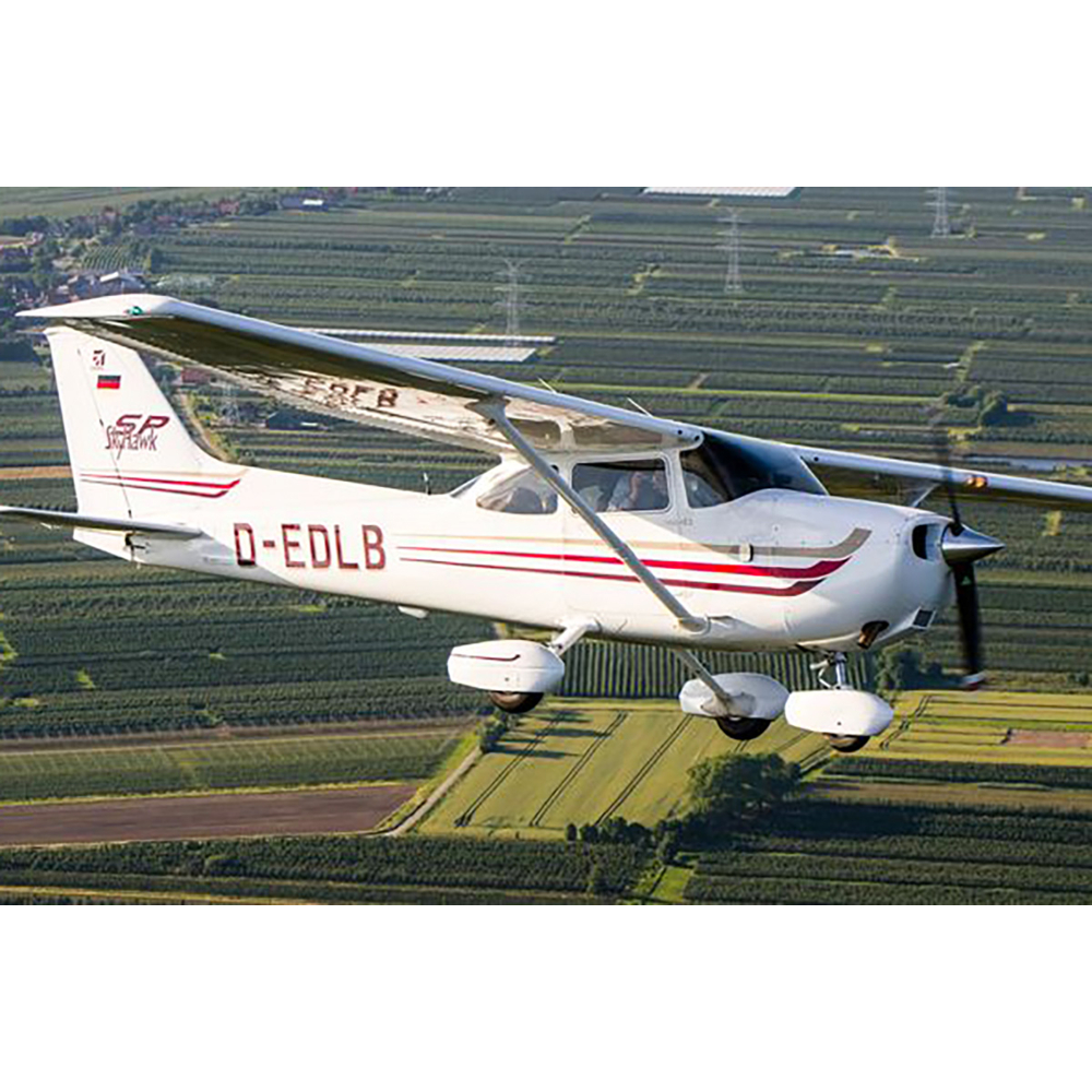 Ein weißes Propellerflugzeug fliegt über ein grünes Ackerland.