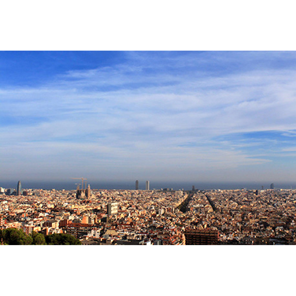 Weitwinkelblick auf eine dichte Stadt mit blauem Himmel und Meer im Hintergrund.