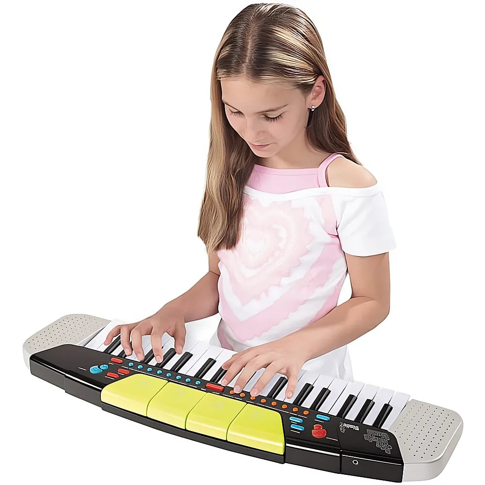 Ein blondes Mädchen in einem rosa-weißen Oberteil spielt konzentriert auf einem Kinderkeyboard mit farbigen Tasten.