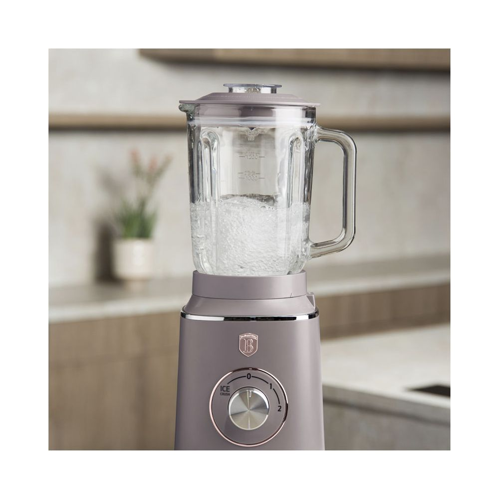 Un blender gris avec un bol en verre rempli d'eau est posé sur un comptoir de cuisine.