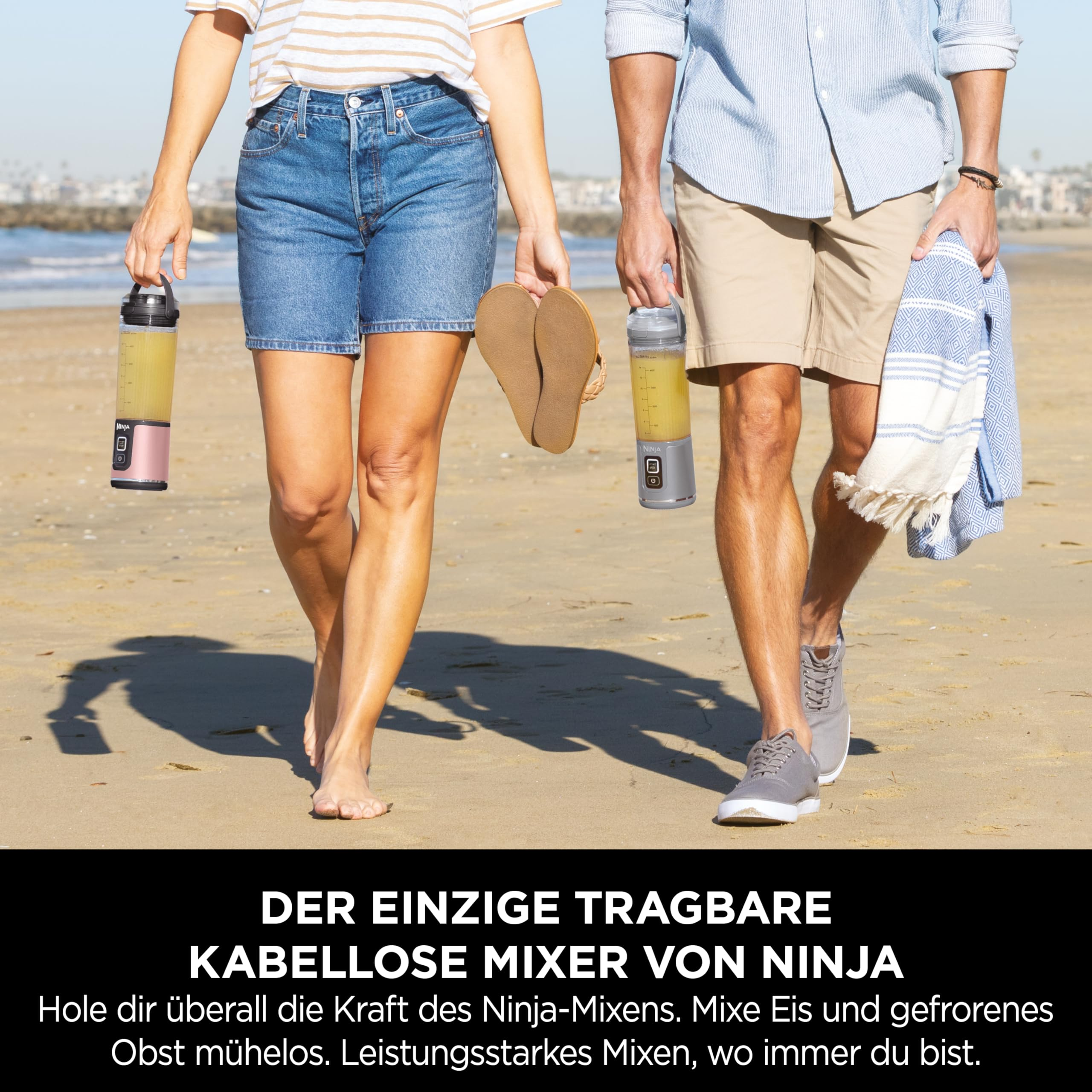 Ein Mann und eine Frau gehen an einem sonnigen Strand und halten tragbare Mixer.