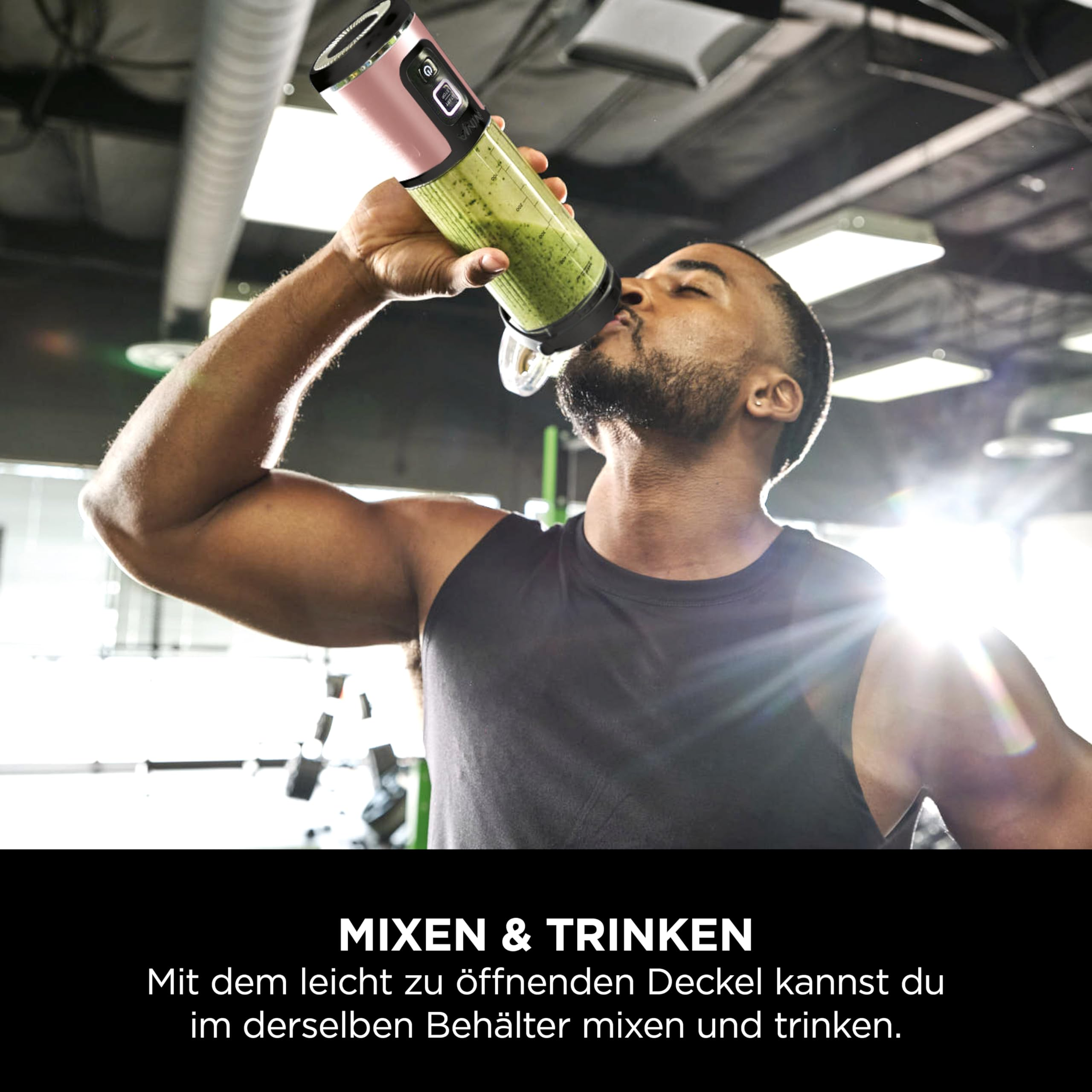 Ein Mann im Fitnessstudio trinkt einen grünen Smoothie aus einem tragbaren Mixer.