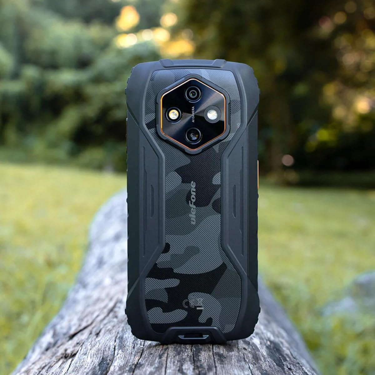 Ein robustes, grau-schwarz gemustertes Ulefone-Smartphone steht auf einem Baumstamm vor einer grünen Naturkulisse.