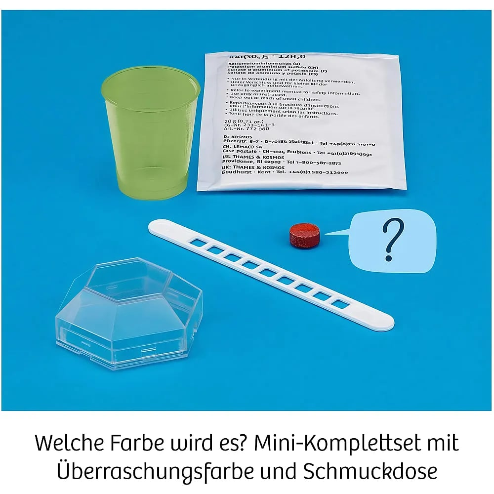 Eingepacktes Experiment mit Becher, chemischem Pulver, Messlöffel, roter Tablette und einer kleinen Schmuckdose.