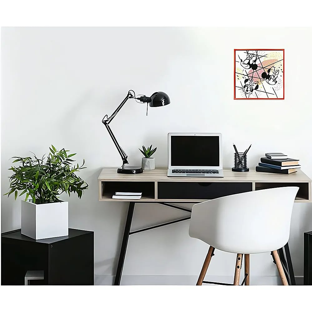 Ein moderner Schreibtisch mit Laptop, schwarzer Lampe, Pflanze und Büchern. Ein weißer Stuhl und ein Bild an der Wand.