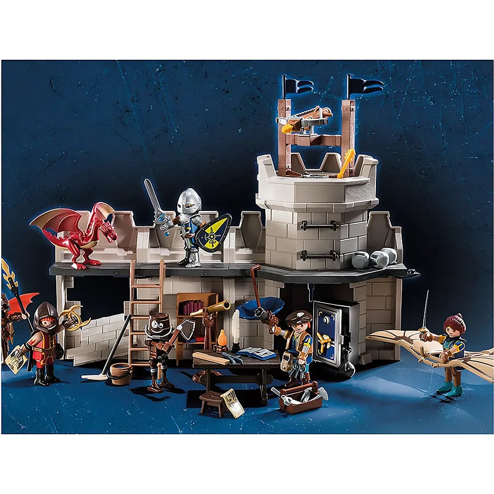 Playmobil-Spielzeugburgszene mit Figuren, einem roten Drachen, einem Ritter mit Schwert und einem Turm vor blauem Hintergrund.