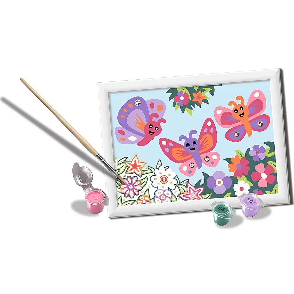 Un lienzo para pintar por números muestra tres mariposas y flores sonrientes, con un pincel y botes de pintura.
