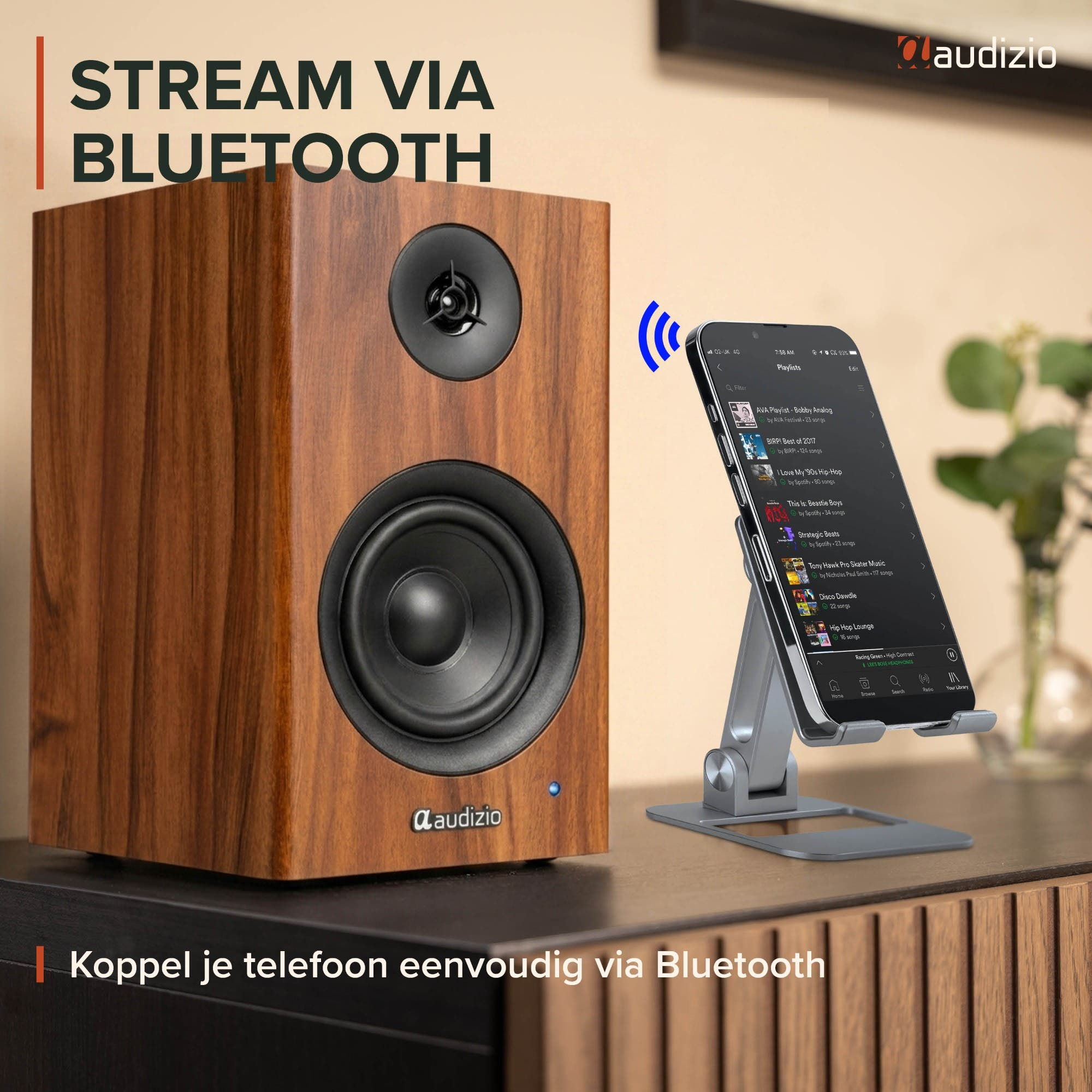 Un altavoz de madera Audizio junto a un teléfono en un soporte, mostrando transmisión por Bluetooth.