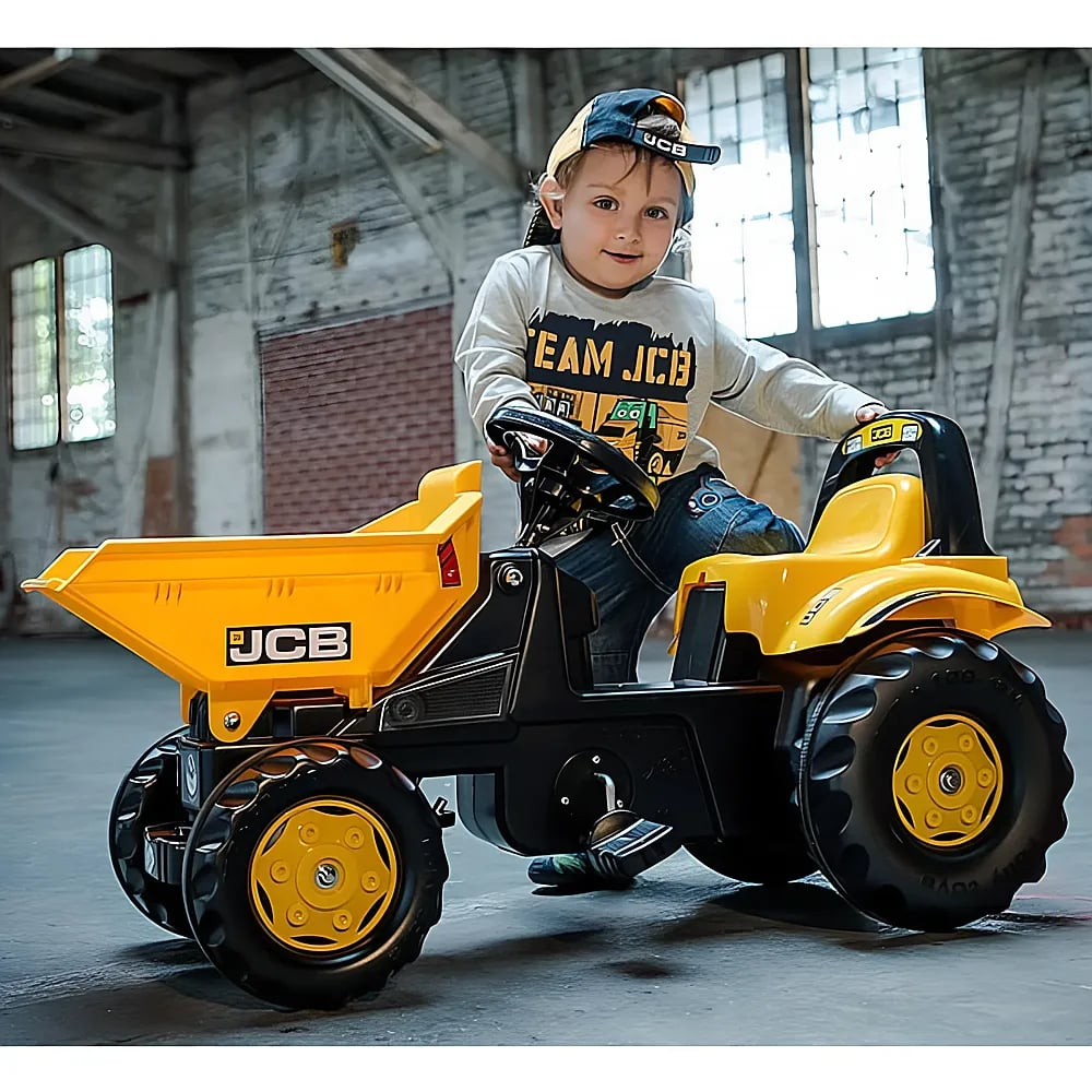 Kleinkind sitzt in einer Lagerhalle auf einem gelb-schwarzen JCB-Spielzeugbagger.