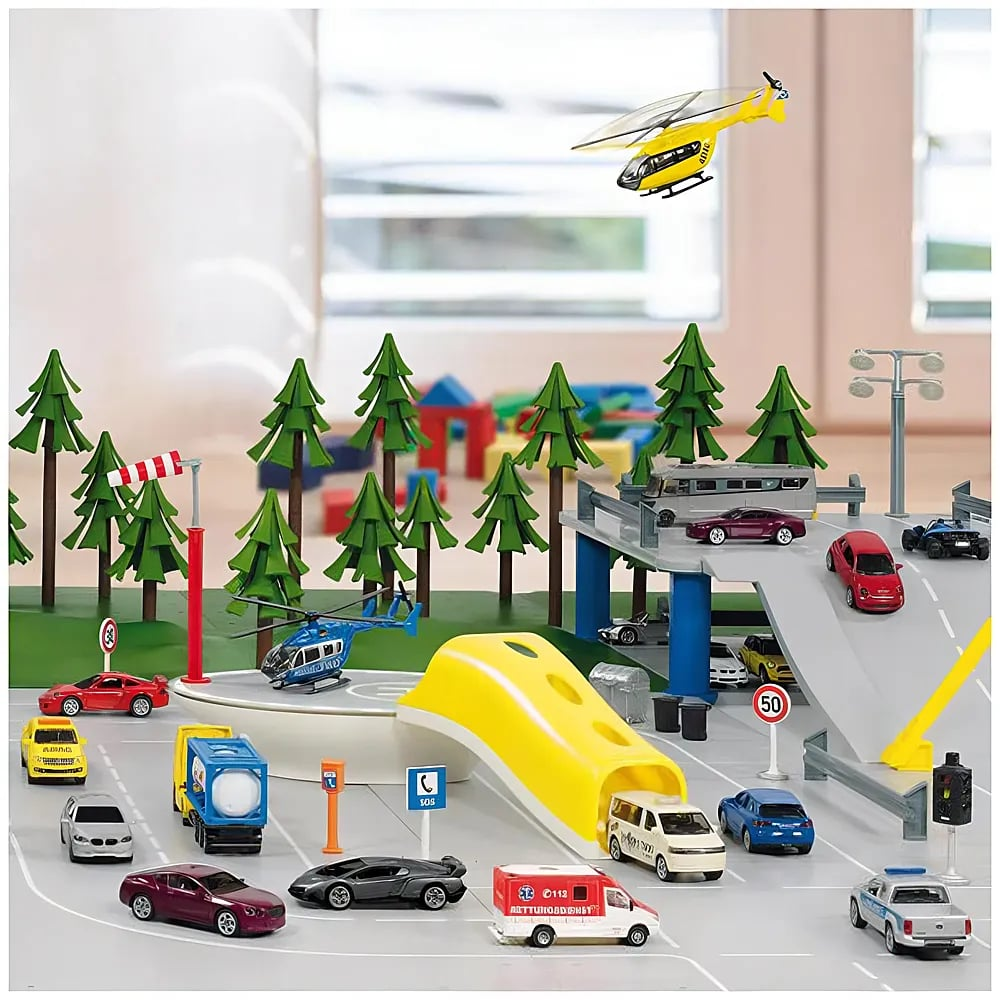 Spielzeugstadt mit Straßen, Autos, Bäumen, Hubschraubern und einer Brücke vor einem Fenster.