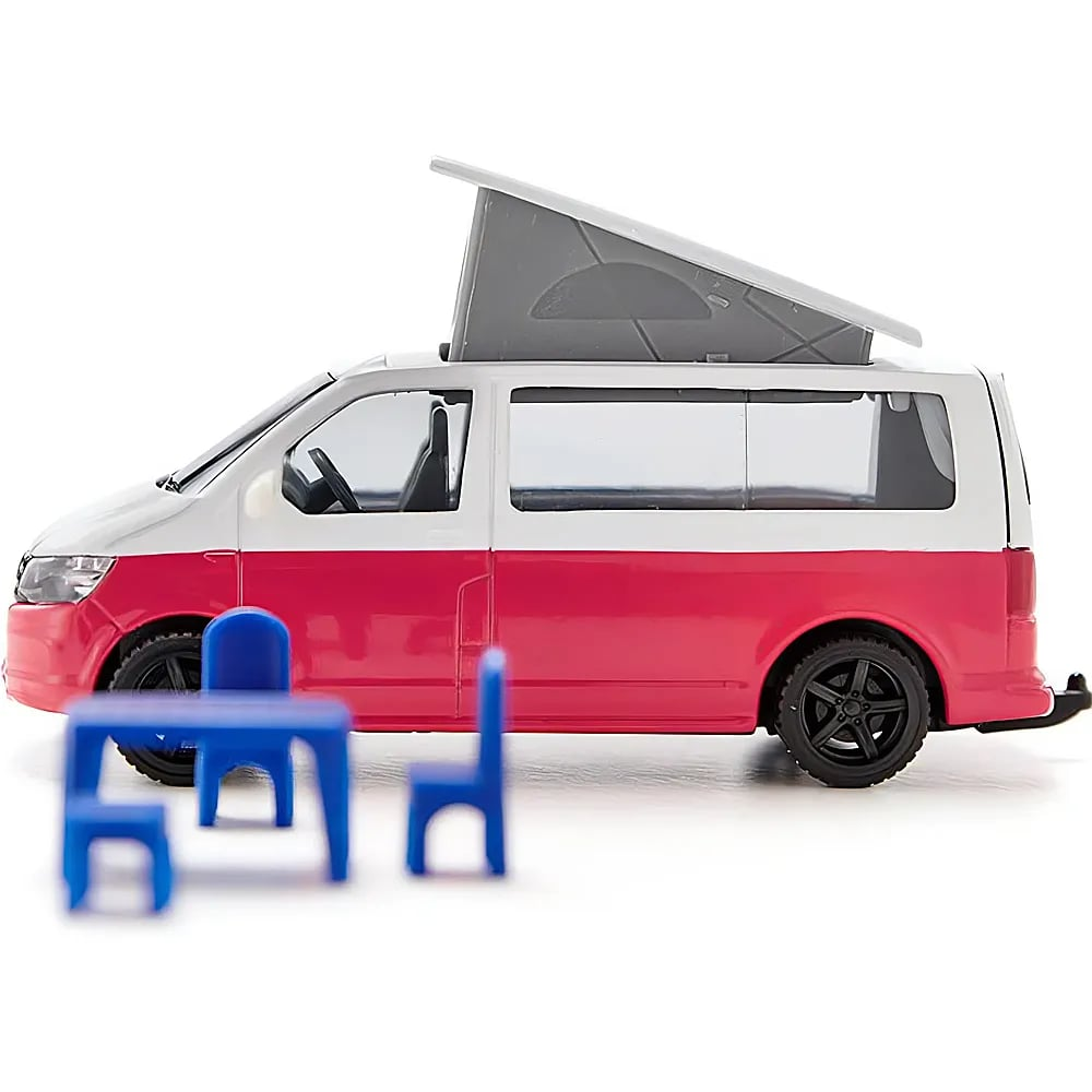 Spielzeug-Wohnmobil in Rot-Weiß mit aufgeklapptem Dach und winzigen blauen Gartenmöbeln im Vordergrund.