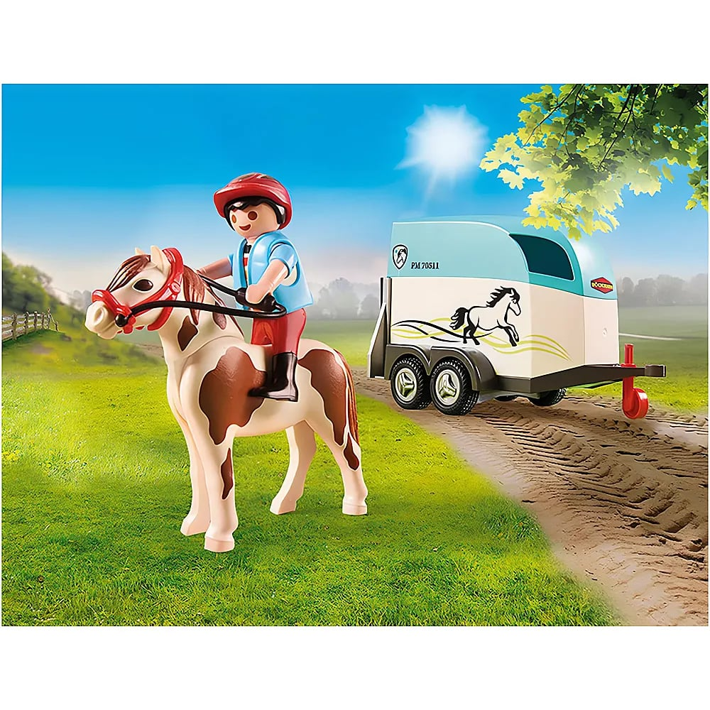 Un personnage Playmobil monte un cheval tacheté à côté d'une remorque pour chevaux sur un chemin.
