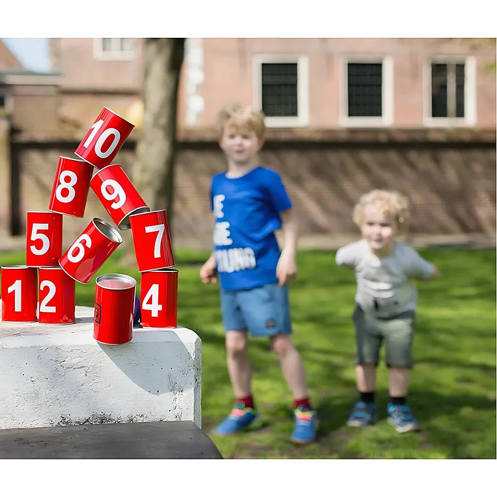 Zwei Jungen spielen draußen neben einem Stapel roter Dosen.
