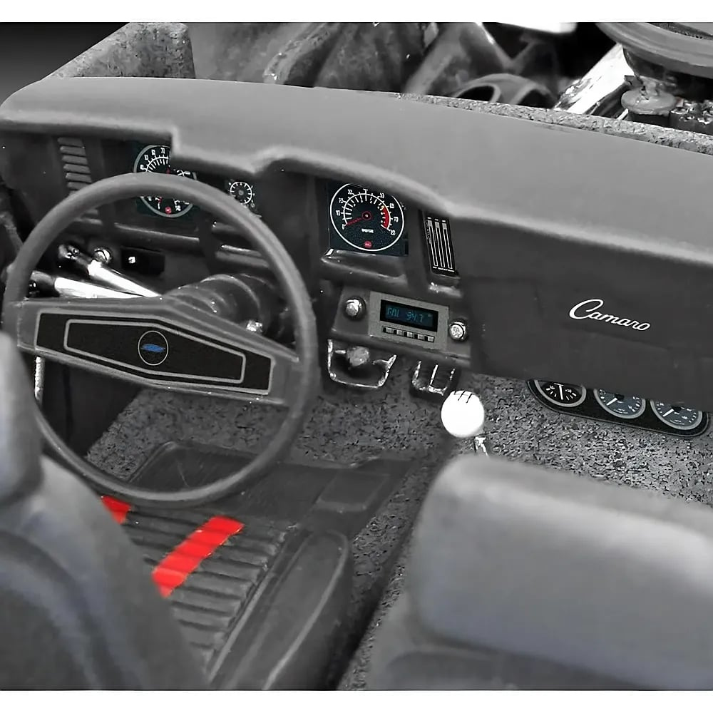 Innenraum eines klassischen Chevrolet Camaro Modells mit Lenkrad, Armaturenbrett und Gangschaltung.