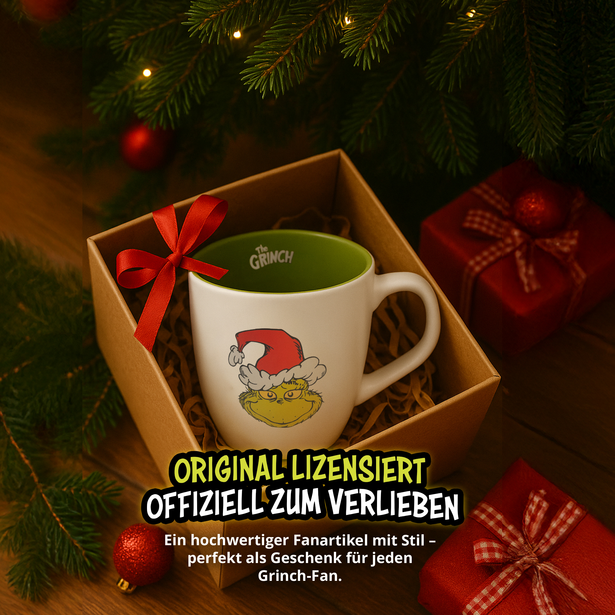 Eine Grinch Tasse in einer Geschenkbox unter einem Weihnachtsbaum mit roter Schleife und Text.